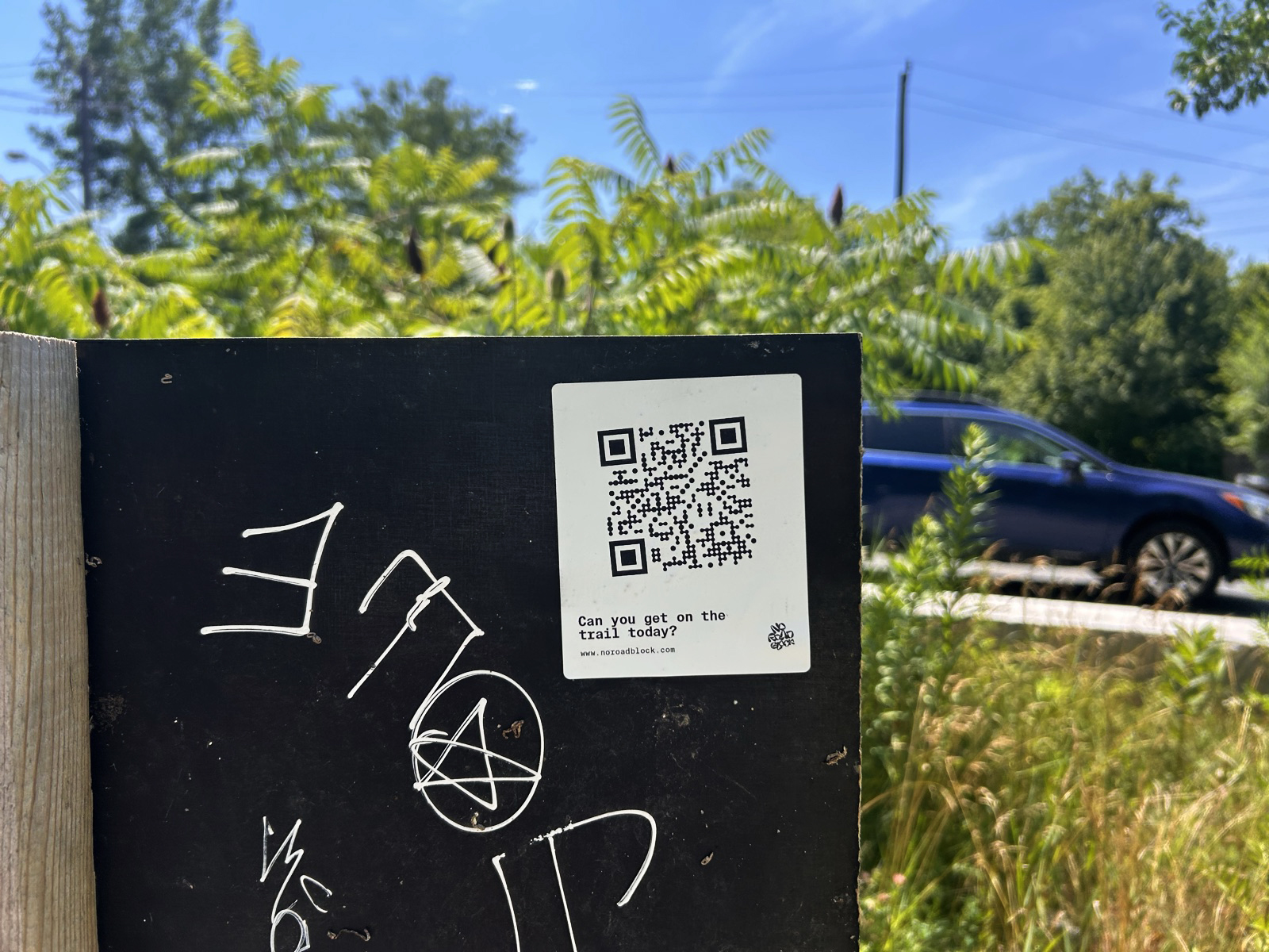 No Road Block sticker on a black trailhead board asking 'Can you get on the trail today?'