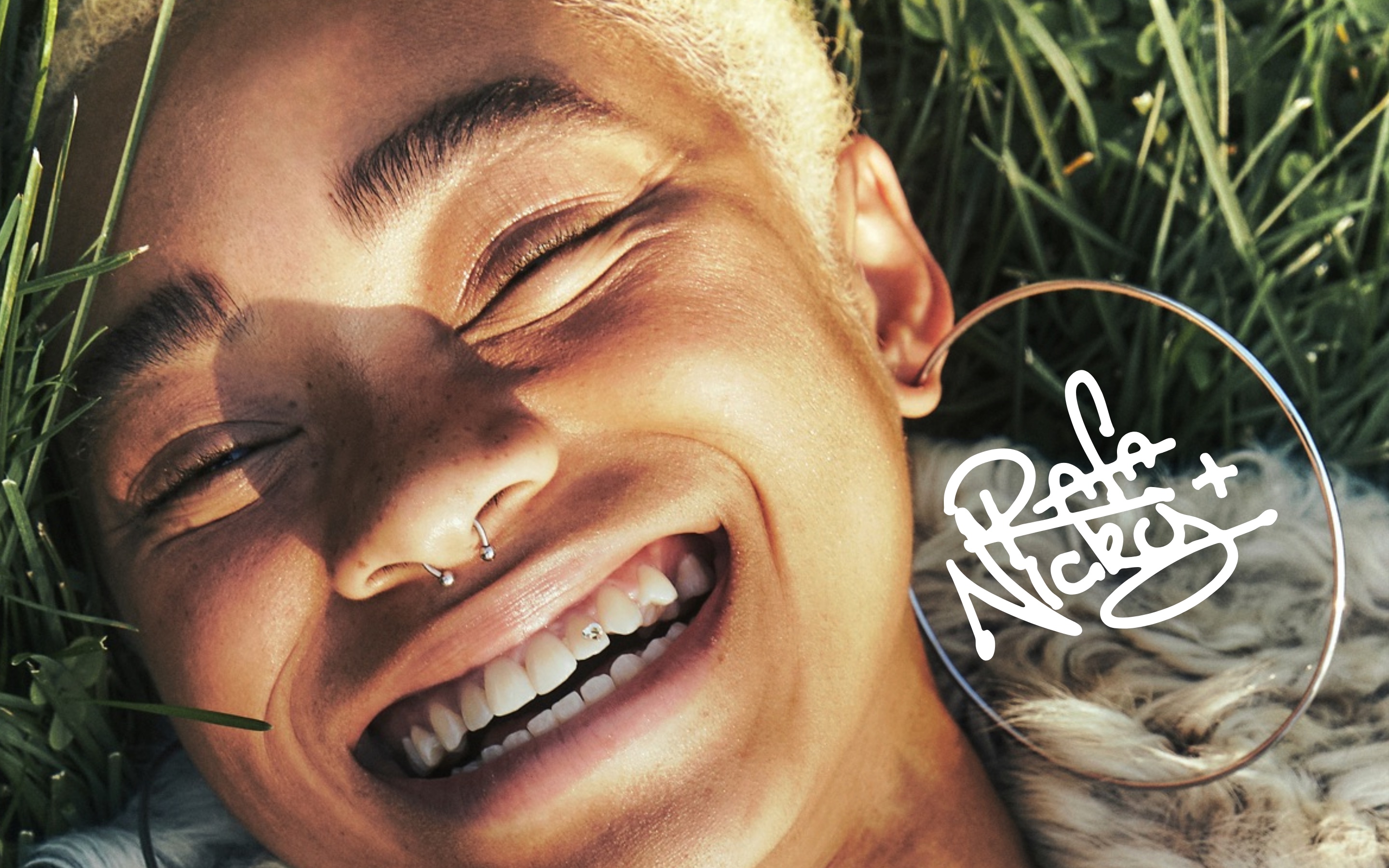 Well Worn Goods editorial photograph by Rafa & Nicky — smiling portrait in the grass, with the Rafa & Nicky signature inside the earring hoop